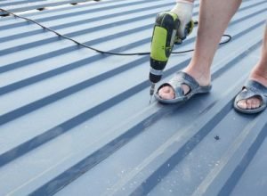 Worker sealing metal roof panels, roof maintenance by Legends Restoration and Group