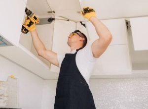 Legends technician fixing kitchen upper cabinet