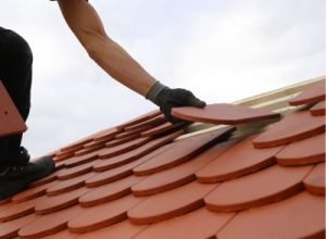 Worker applying roof tiles, roof installation by Legends Restoration and Group
